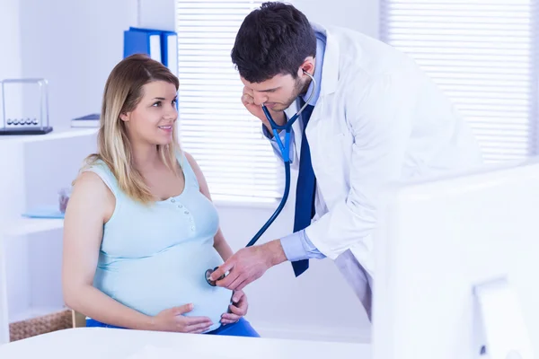 Doctor examining stomach of pregnant patient