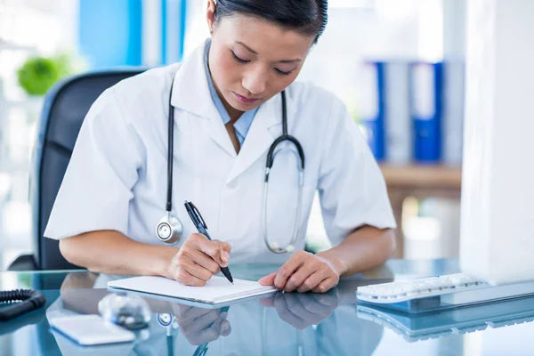 Concentrated doctor writing on notebook