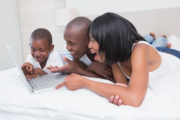 Pretty family using laptop together in bed