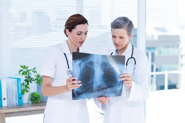 Concentrated medical colleagues examining x-ray together