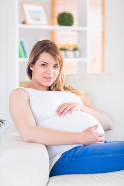 Pregnant woman looking at camera on the couch