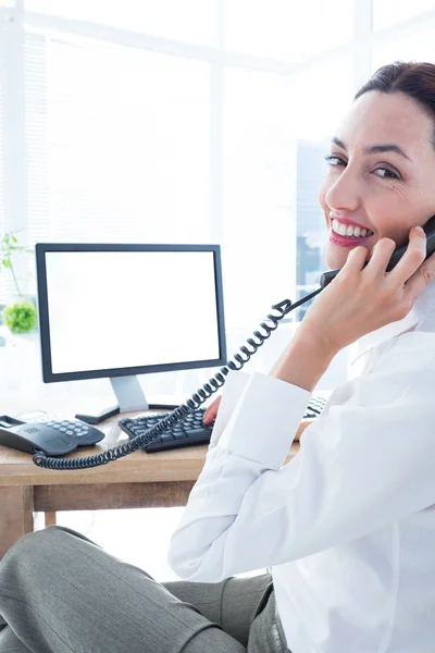 Smiling businesswoman using computer and phoning