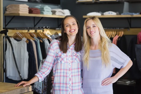 Two female friends standing together and smiling at camera