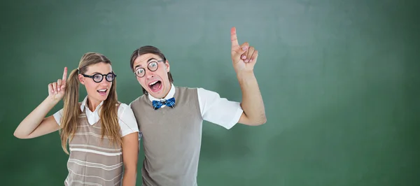 Geeky hipsters pointing against chalkboard