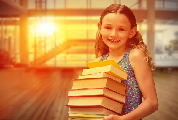 Little girl carrying books in library