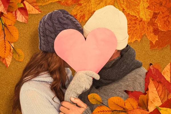 Couple in warm clothing holding heart