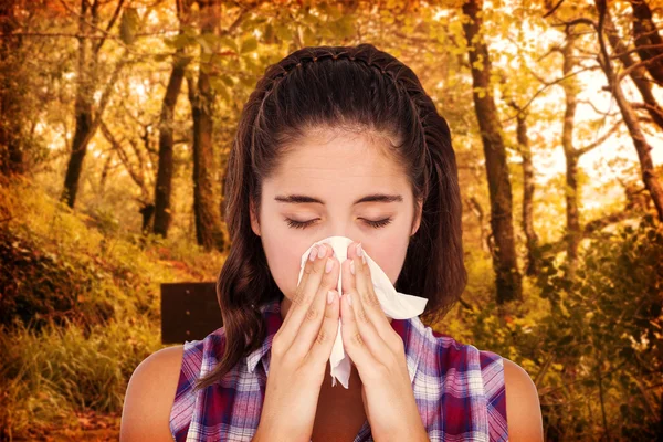 Close-up of sick woman sneezing in a tissue