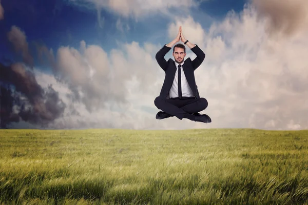 Businessman sitting in lotus pose with hands