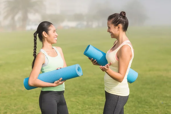 Women with exercise mats chatting