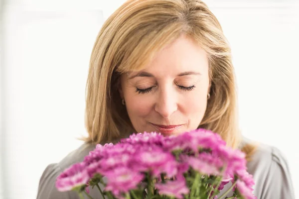 Casual businesswoman smelling at flowers