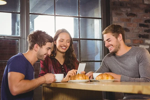 Smiling friends enjoying coffee and croissants together