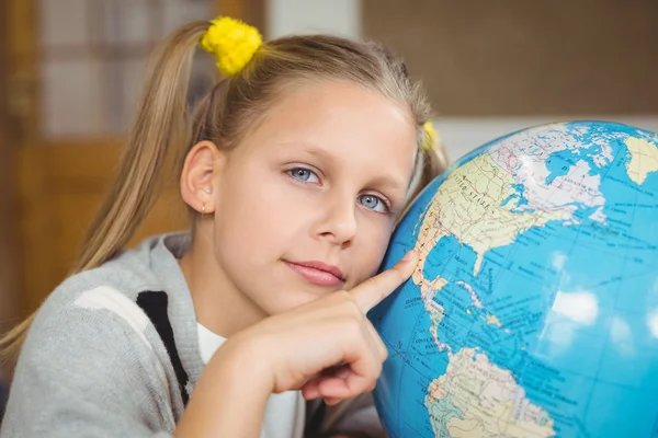 Pupil pointing on globe in classroom