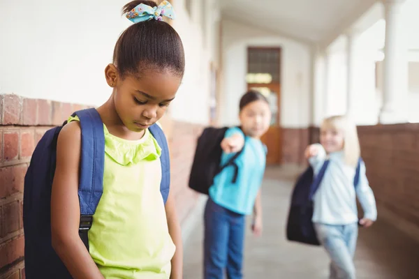 Sad pupil being bullied by classmates at corridor