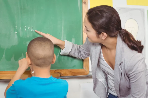 Teacher helping pupil at chalkboard