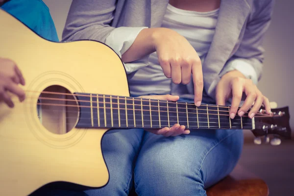 Teacher giving guitar lessons to pupil