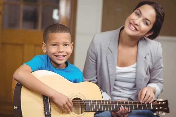 Pretty teacher giving guitar lessons to pupil