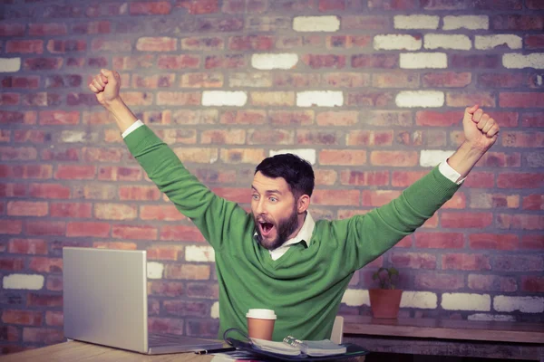 Businessman cheering while looking at laptop