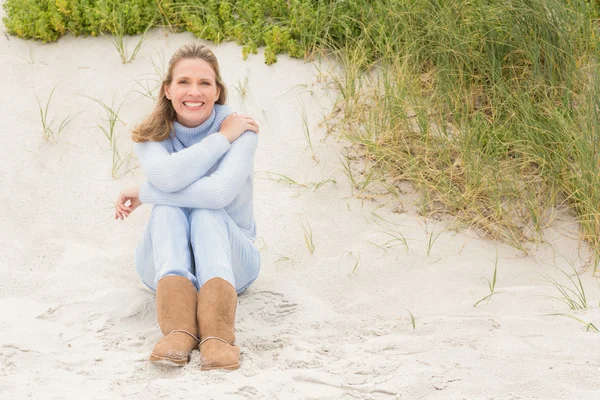 Smiling woman sitting on sand