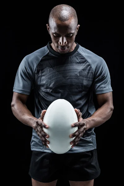 Thoughtful athlete looking at rugby ball