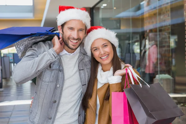 Couple holding shopping bags with christmas hats