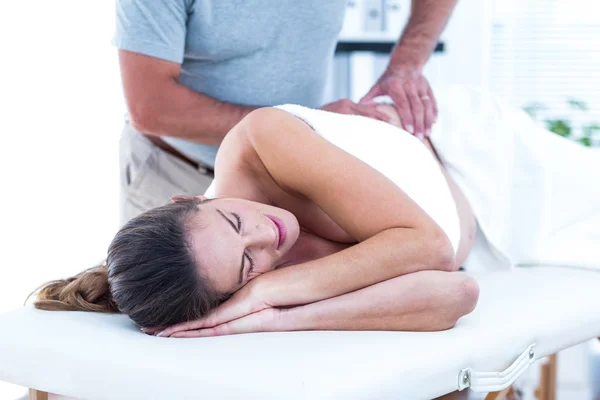 Masseur giving massage to woman in spa