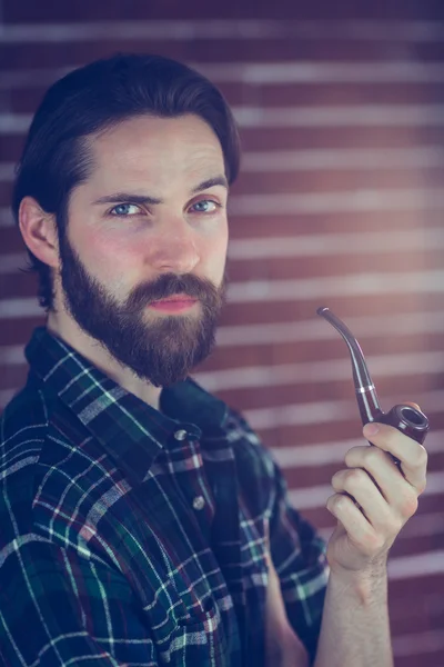 Confident hipster smoking pipe