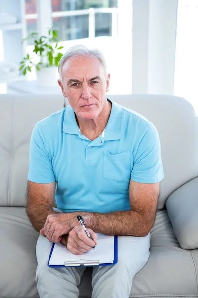 Thoughtful senior man with clipboard