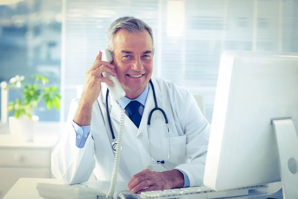 Male doctor in conversation through telephone