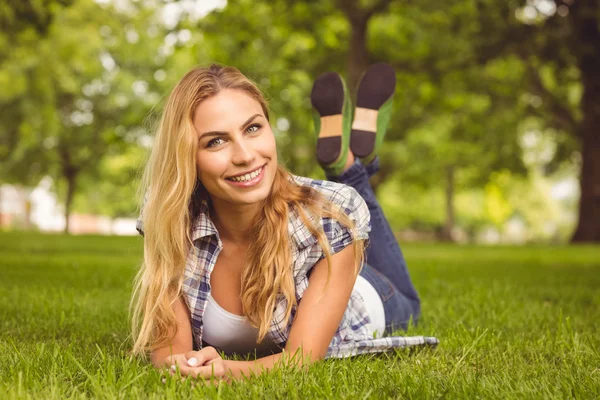 Portrait of smiling woman lying on front at park