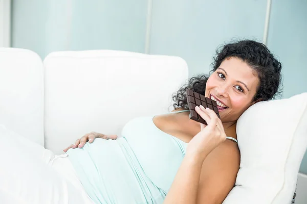 Happy pregnant woman eating chocolate bar