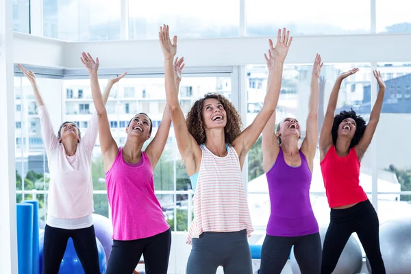 Portrait of happy women exercising with arms raised