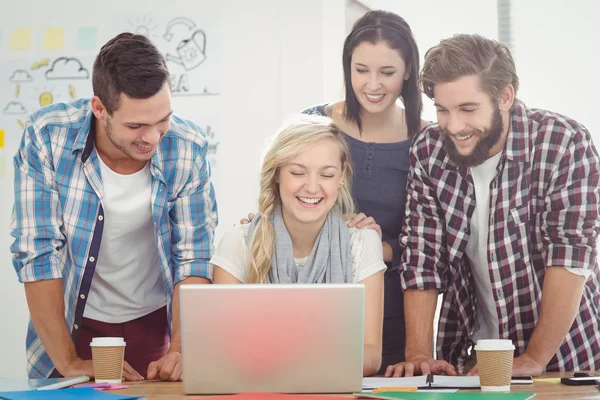 Smiling colleagues working on laptop