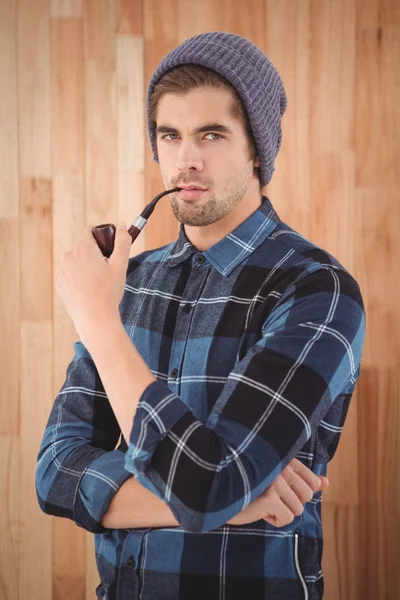 Portrait of hipster holding smoking pipe