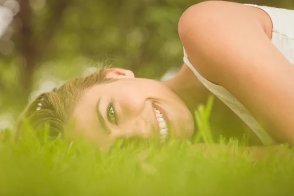 Side view of beautiful happy woman lying on grass