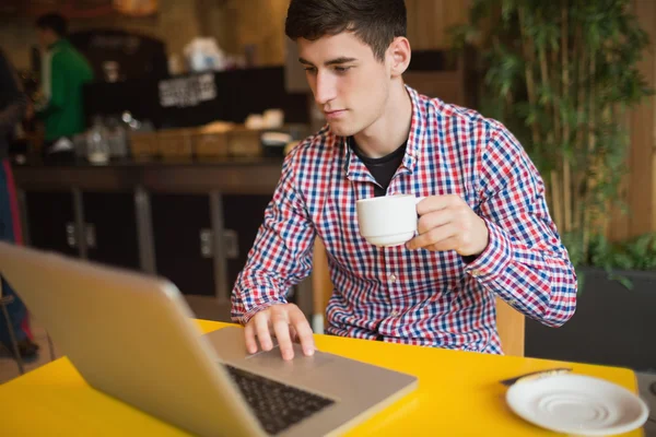 Young man with coffee using laptop