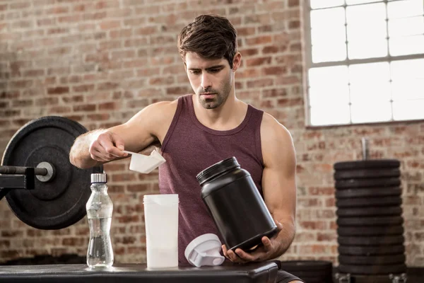 Man adding supplement from tin to bottle