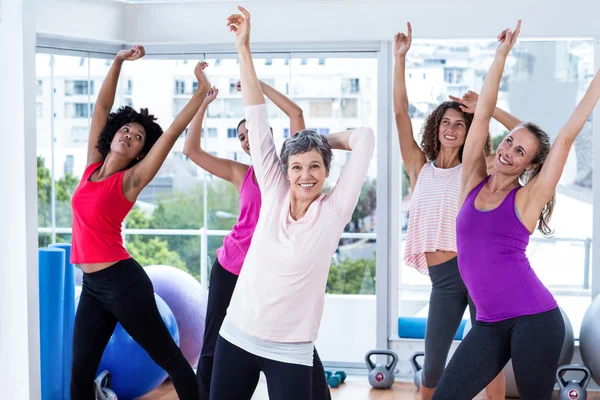 Group of cheerful women exercising with arms raised
