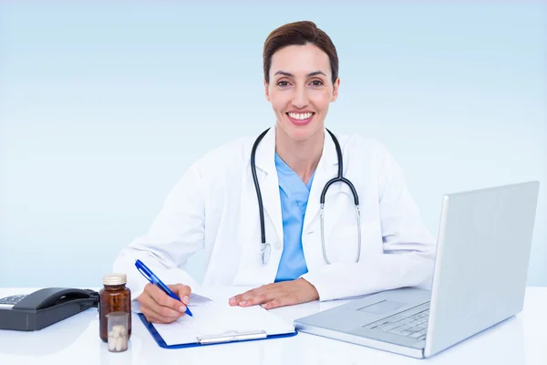 Portrait of smiling female doctor writing on pad