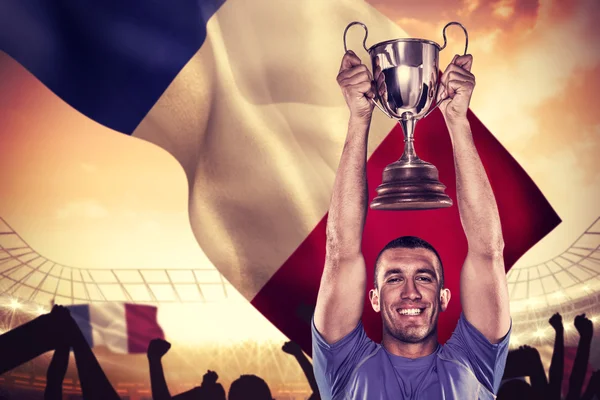 Portrait of smiling rugby player holding trophy