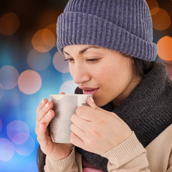 Smiling brunette drinking hot beverage