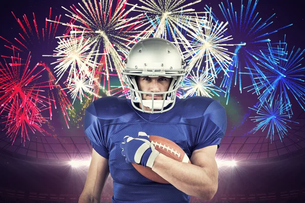 American football player holding ball against fireworks exploding
