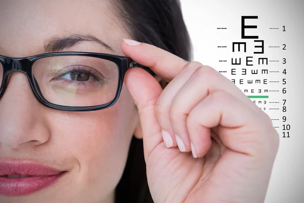 Pretty brunette wearing eye glasses against eye test