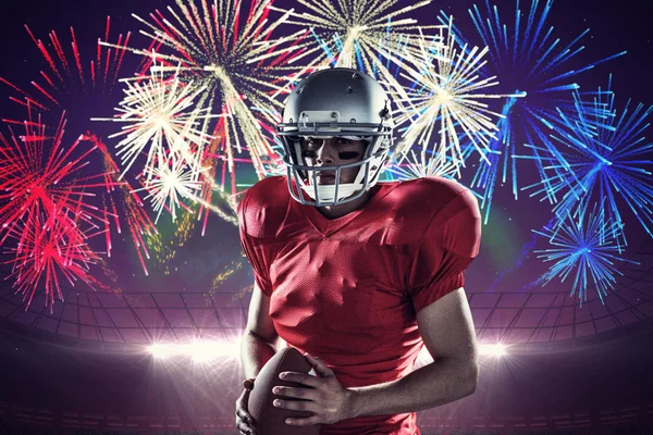 Determined sportsman with American football against fireworks exploding