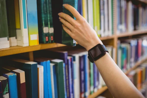 Student picking book in library wearing smart watch