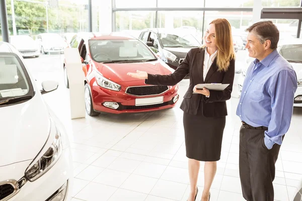 Smiling businesswoman showing car to customer