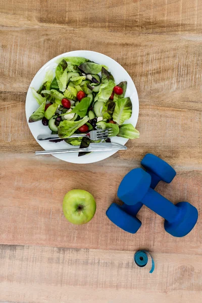 Salad, apple and dumbbells