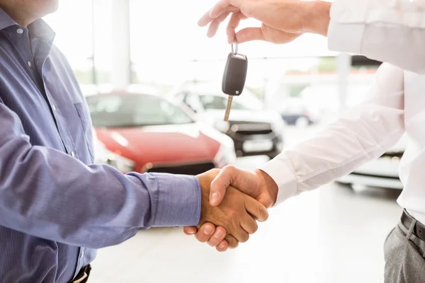 Businessman giving car key shaking customer hand