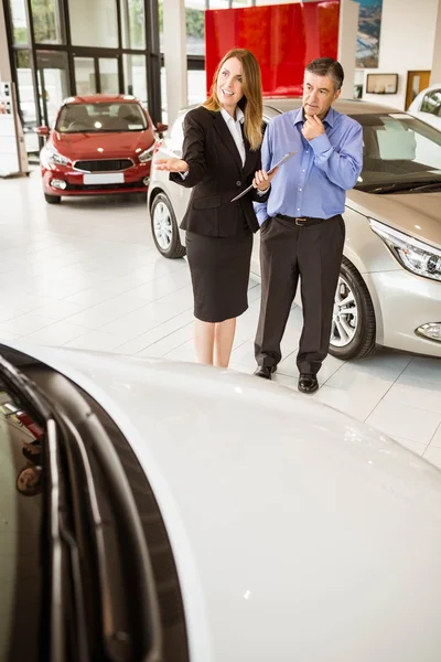 Smiling businesswoman showing car to customer