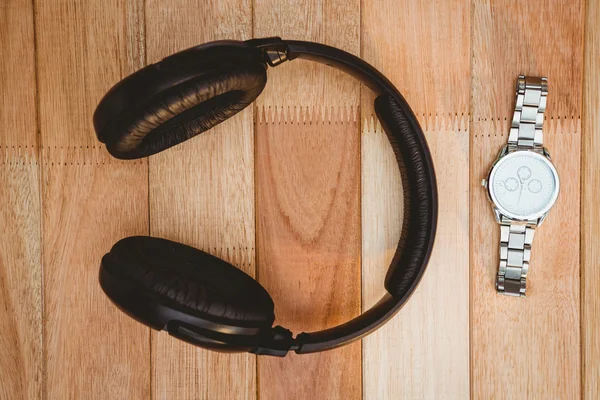 Headphones and watch on wood desk