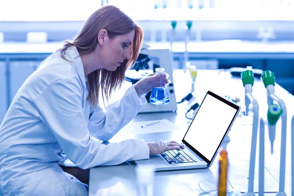 Scientist looking at beaker of chemical